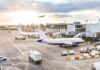 Airplanes at airport gates during sunset with ground vehicles and jet bridges