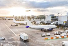 Airplanes at airport gates during sunset with ground vehicles and jet bridges