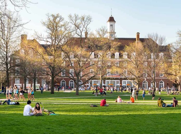 Students relaxing on a campus quad in front of a brick academic building