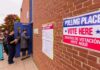 Voters line up outside a brick building polling place