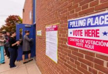 Voters line up outside a brick building polling place
