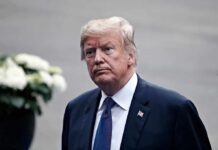 A Growing Rift Splits the America First Right man in a suit with an American flag pin