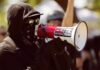 Protester in black clothing speaking into a megaphone
