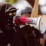 Protester in black clothing speaking into a megaphone