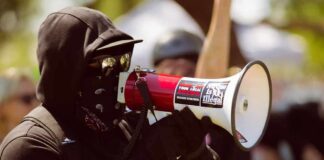 Protester in black clothing speaking into a megaphone