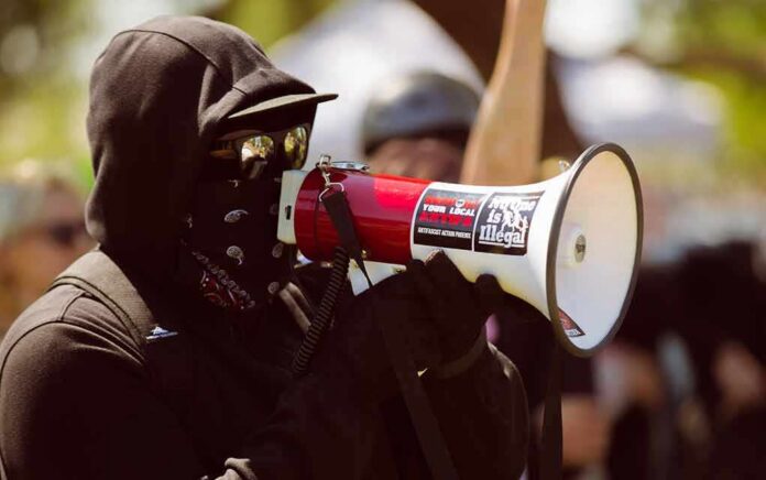Protester in black clothing speaking into a megaphone
