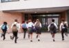 Students in uniforms running toward a school entrance