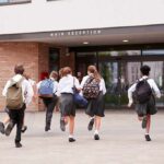 Students in uniforms running toward a school entrance