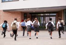 Students in uniforms running toward a school entrance