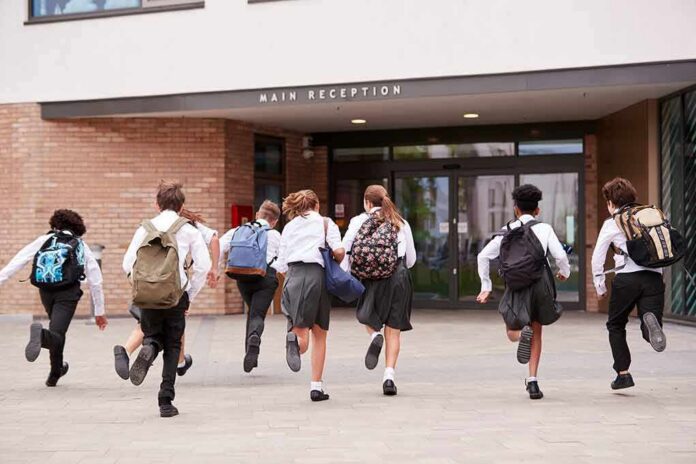 Students in uniforms running toward a school entrance