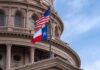 Texas and U.S. flags in front of a capitol building dome