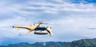 Cargo drone helicopter flying over green mountain range