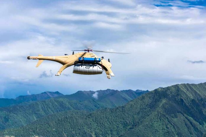 Cargo drone helicopter flying over green mountain range