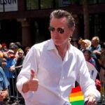 Man in white shirt giving thumbs up at a pride parade