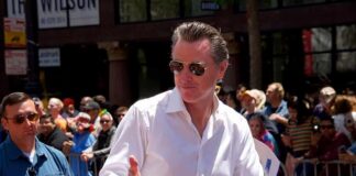 Man in white shirt giving thumbs up at a pride parade