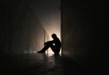 Silhouette of a person sitting on the floor in a dim hallway