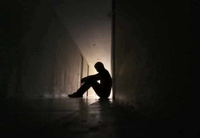 Silhouette of a person sitting on the floor in a dim hallway