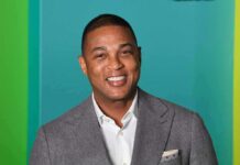 smiling man in gray suit against teal background