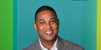 smiling man in gray suit against teal background