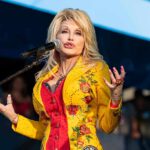 Singer performing on stage in a bright yellow floral jacket