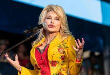 Singer performing on stage in a bright yellow floral jacket