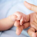baby hand holding adult finger