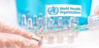 Gloved hands holding vaccine vial and syringe near WHO banner
