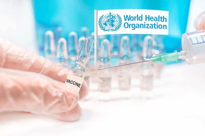 Gloved hands holding vaccine vial and syringe near WHO banner