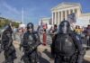 Riot police stand in front of a courthouse during a protest