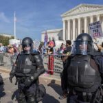 Riot police stand in front of a courthouse during a protest