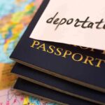 Stack of passports with a note labeled deportation on top, placed on a map