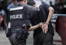 Police officer escorting handcuffed man to a vehicle
