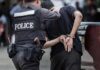 Police officer escorting handcuffed man to a vehicle