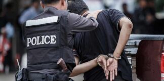 Police officer escorting handcuffed man to a vehicle