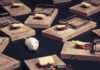 A white mouse navigating among several wooden traps with cheese bait