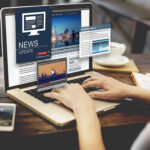 Person reading news websites on a laptop.