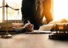 Lawyer writing at desk with scales and gavel