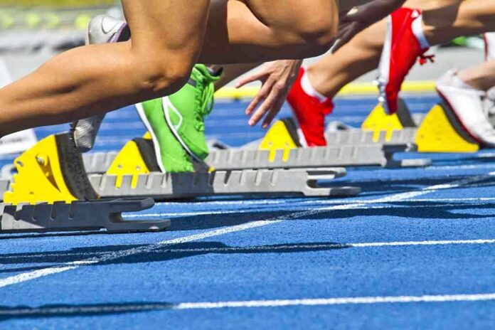 Athletes starting a sprint from starting blocks on a blue track