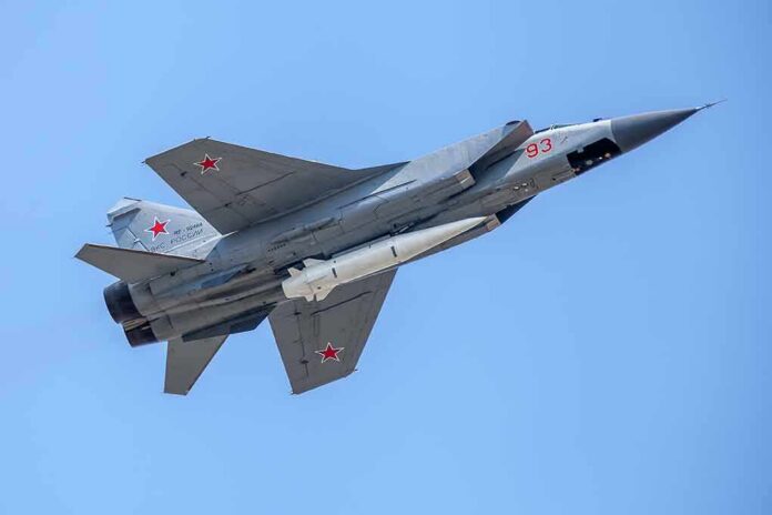 fighter jet with missile flying against a clear blue sky