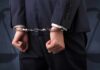 Businessperson in handcuffs with hands behind back