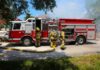 Fire truck with firefighters operating hoses on a residential street