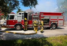 Fire truck with firefighters operating hoses on a residential street