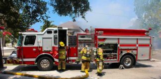 Fire truck with firefighters operating hoses on a residential street