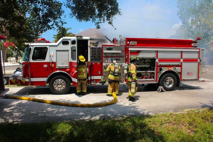 Fire truck with firefighters operating hoses on a residential street