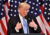 Donald Trump speaking at a podium with American flags behind him