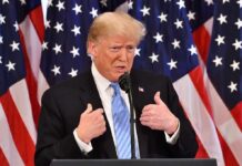 Donald Trump speaking at a podium with American flags behind him