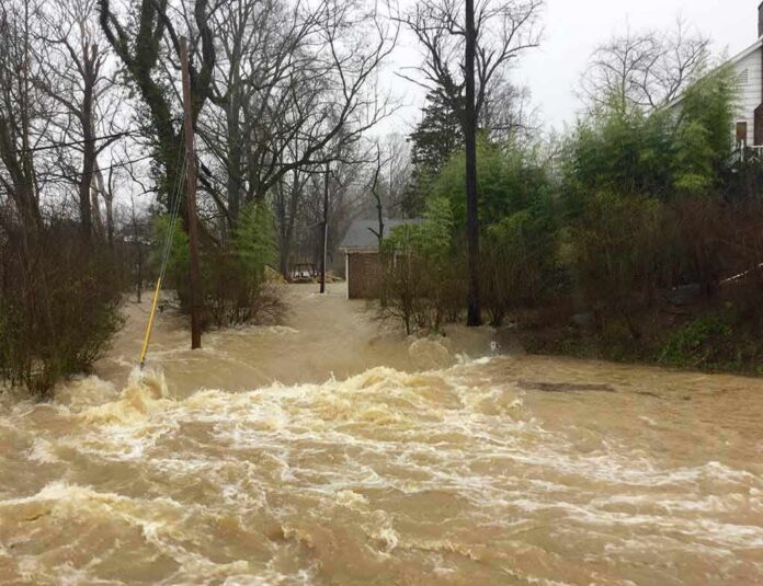 shutterstock_1321316804 Flooded residential street with fast-moving muddy water