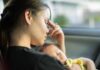 Woman resting in a car while holding a sleeping baby
