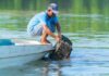 Fisherman retrieving a crab trap from the water beside a small boat
