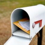 White mailbox with red flag holding envelopes and padded mailers